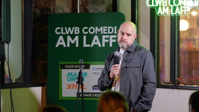 A stand-up comedian performing on stage at a comedy club event.